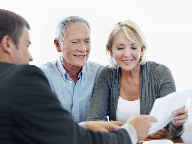 A friendly financial broker showing a senior couple a document